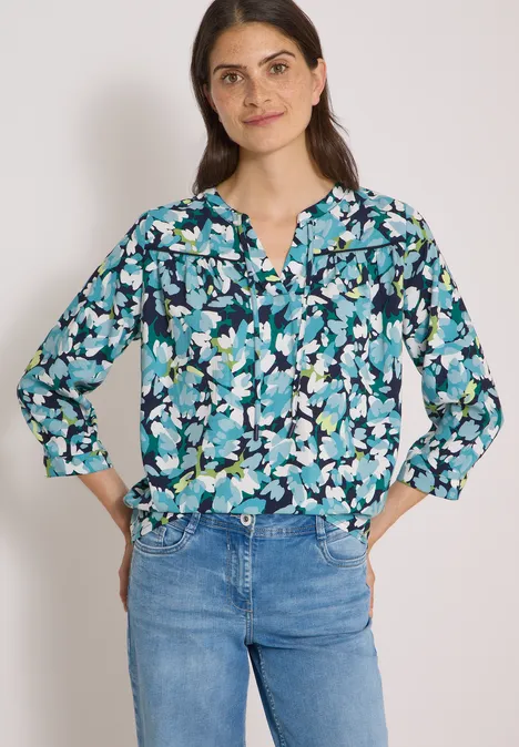3/4-Arm Tunika mit Split Neck und Print urban dark blue Eine Frau trägt eine marineblaue Bluse mit türkis-weißen Blumen und lässige Jeans.