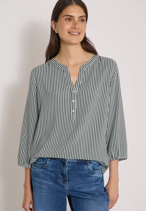 3/4-Arm Bluse mit Split Neck und Streifen khaki Frau mit grüner, gestreifter Bluse und blauen Jeans vor hellem Hintergrund.
