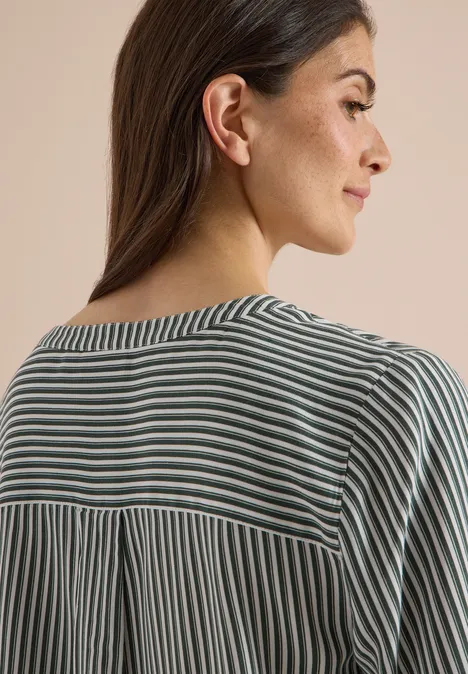 3/4-Arm Bluse mit Split Neck und Streifen khaki Frau von schräg hinten, trägt gestreiftes Oberteil in Grau-Weiß, vor einem einfarbigen Hintergrund.