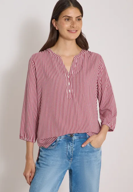 3/4-Arm Bluse mit Split Neck und Streifen russet red Frau in rot-weiß gestreifter Bluse mit Knopfleiste und blauen Jeans, lächelnd vor neutralem Hintergrund.