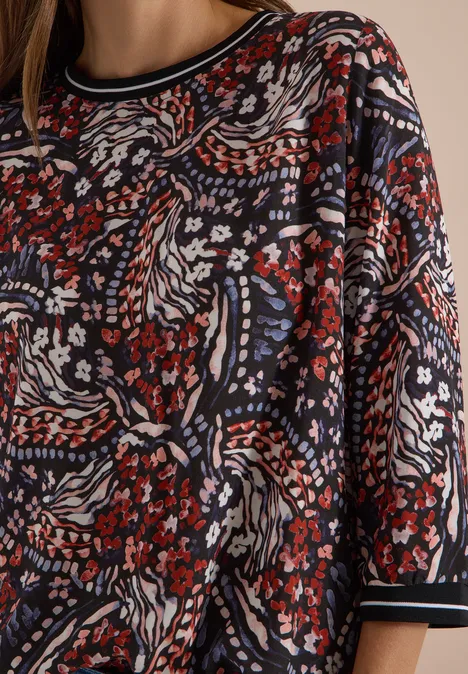 Dunkles Shirt mit abstraktem floralen Muster in Rot, Weiß, Blau und Schwarz.