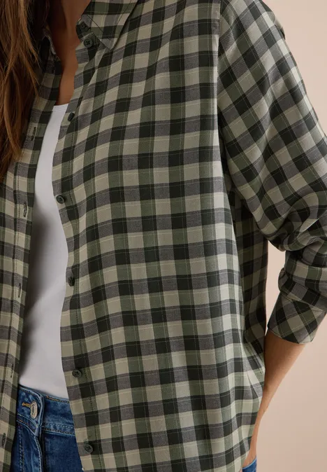 Overhemd met lange mouwen en ruitjespatroon khaki Frau im grün-beige karierten Hemd über weißem Top und Jeans.