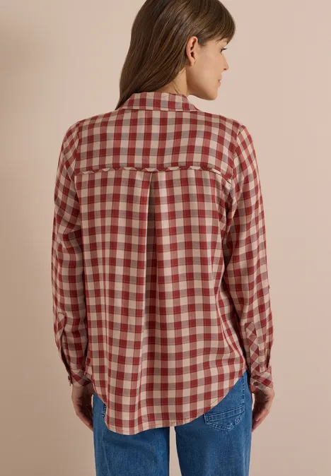 Rückansicht einer Person in kariertem langärmeligem Hemd und Jeans.