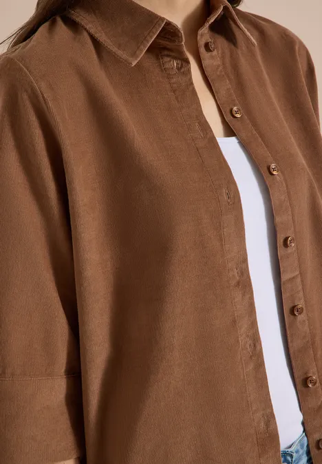 Chemisier à manches courtes uni creamy mocha Braunes Hemd aus Leinen mit Knöpfen über weißem T-Shirt, Nahaufnahme des Oberkörpers.