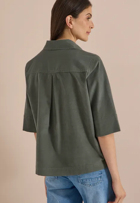 Chemisier à manches courtes uni dried olive green Frau von hinten in grünem Cordhemd mit ¾-Ärmeln und blauen Jeans.