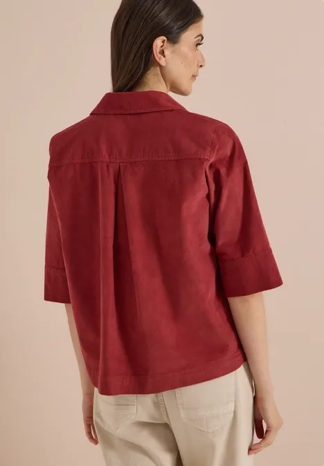 Chemisier à manches courtes uni russet red Rückenansicht einer Frau in rotem 3/4-Arm-Hemdjacke und beigen Hosen.