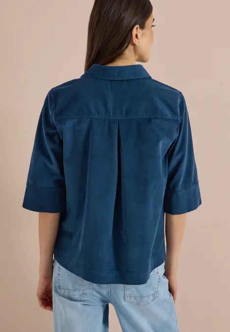 Chemisier à manches courtes uni moonlight blue Frau von hinten in dunkelblauer Halbarmbluse mit Rückenfalte, kombiniert mit hellen Jeans.