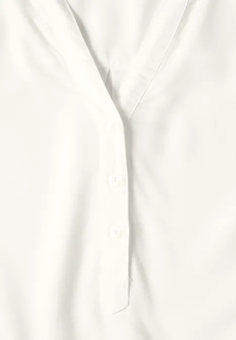 Gros plan d’un chemisier blanc avec patte de boutonnage et col en V.