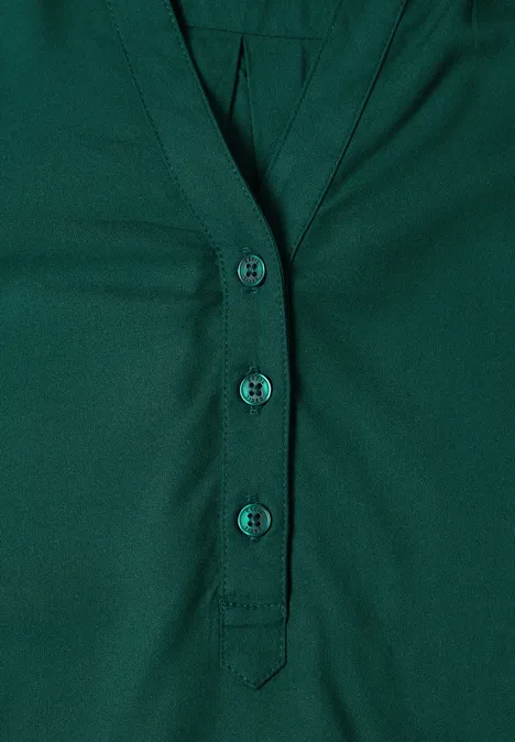 Dunkelgrünes Shirt mit V-Ausschnitt und drei Knöpfen in einer schlichten Knopfleiste.