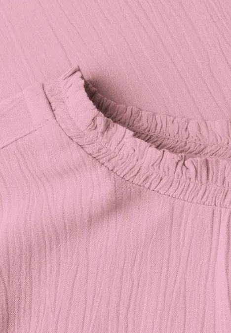 Close-up van een roze, gestructureerde stof met een geplooide kraag