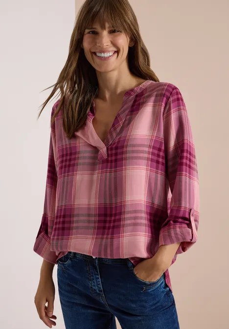 Langarm Tunika mit Karomuster velvet rose Eine lächelnde Frau trägt eine pink karierte Bluse und Jeans vor hellem Hintergrund.