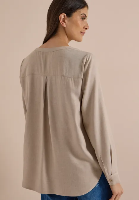Frau trägt lockere beige Bluse mit langen Ärmeln, Rückenansicht und seitlicher Blick.