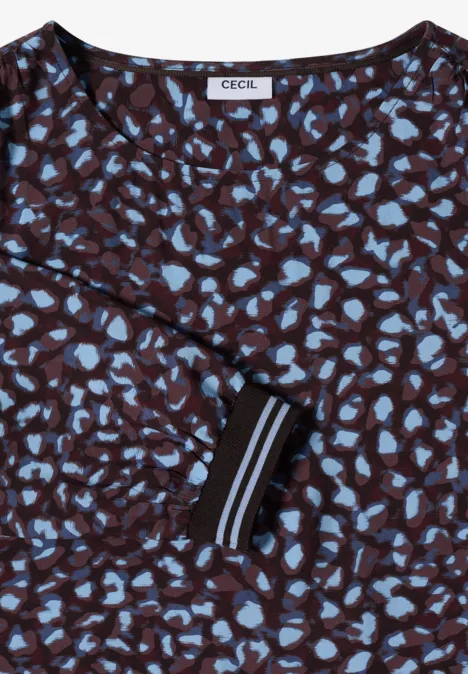 Dunkelbraune Bluse mit hellblauen, abstrakten Herzmustern und kontrastierendem schwarz-weiß gestreiftem Ärmelbündchen.