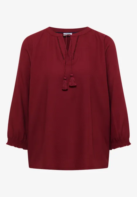 Elegante burgunderrote Bluse mit 3/4-Ärmeln und Quasten am Ausschnitt.