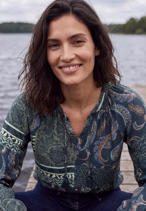 Langarm Tunika mit Bändern und Print urban dark blue Lächelnde Frau mit dunklen Haaren und gemustertem Oberteil am Ufer eines Sees.