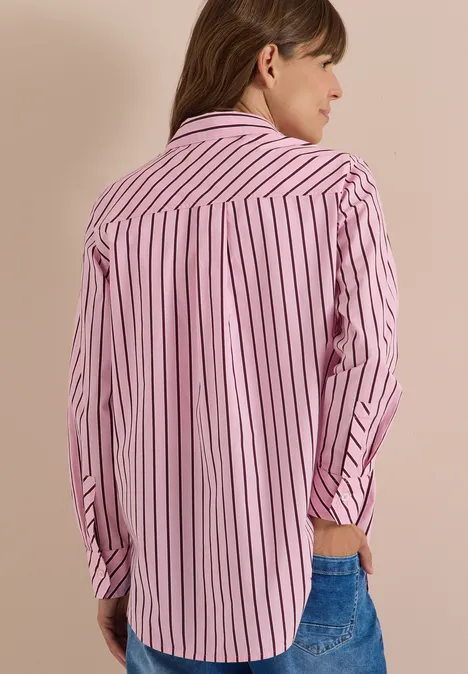 Eine Person von hinten in rosa-weiß gestreiftem Hemd und Jeans.