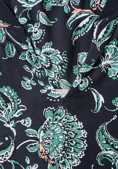 Blouse met lange mouwen, split in de hals en print urban dark blue Close-up van een zwarte stof bedrukt met gestileerde groene en witte bloemen.