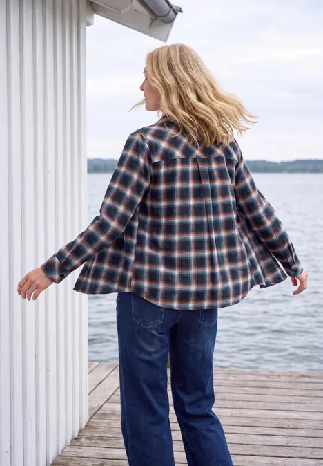 Flanellen blouse met lange mouwen en ruitjespatroon urban dark blue Vrouw in geruit overhemd en spijkerbroek loopt op een houten steiger bij een wit hutje aan het water.