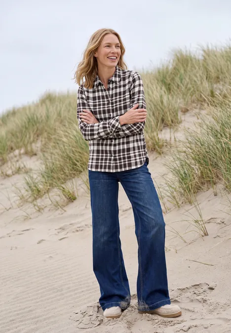 Langarm Flanell Bluse mit Karomuster truffle brown Eine lächelnde Frau in kariertem Hemd und weitem Jeans steht auf einer Sanddüne mit Strandgras.