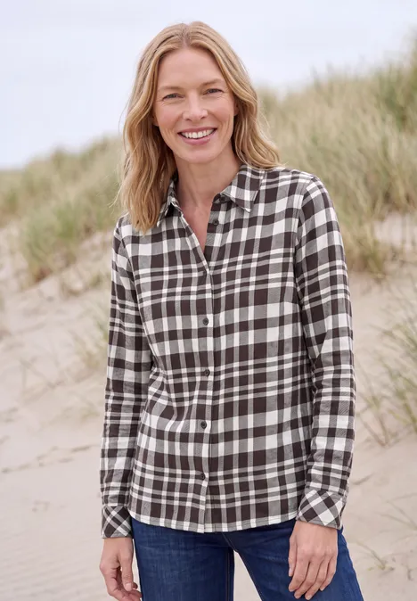 Langarm Flanell Bluse mit Karomuster truffle brown Frau mit kariertem Hemd lächelt am Strand vor Dünen.