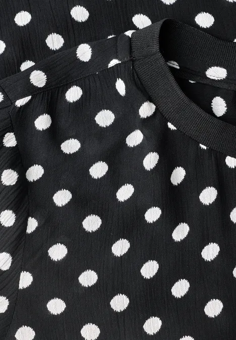 Schwarzes, geripptes Oberteil mit weißen Polka-Dots und Rundhalsausschnitt.