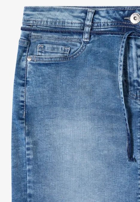 Lichtblauwe spijkerbroek in close-up met ceintuurlus, zijzak en zichtbare knoop