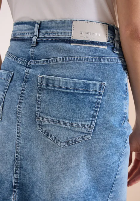 Achteraanzicht van een lichtblauwe denimrok met achterzakken en riemlussen.