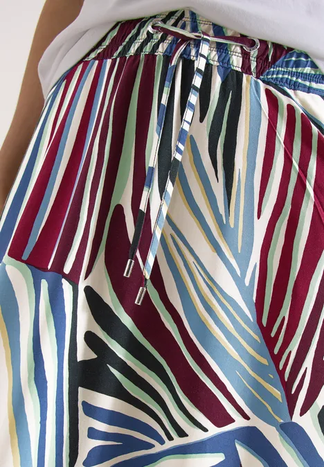 Nahaufnahme eines bunten Stoffmusters mit gestreiften, blattähnlichen Formen und verschnürtem Bund.