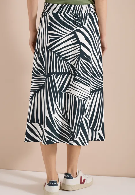 Witte midi-rok met zwart abstract bladprint, elastische tailleband, uitlopend model, gecombineerd met sneakers.