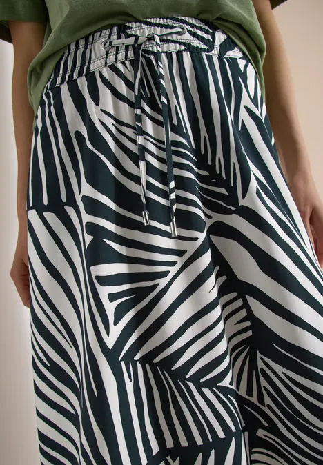 Loszittende broek met zwart-witte zebraprint, elastische tailleband en koordsluiting.