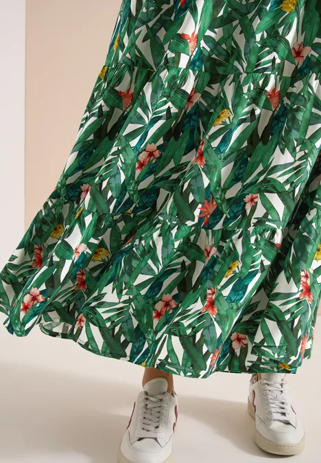 Groene rok met tropische bladprint, gecombineerd met witte sneakers.