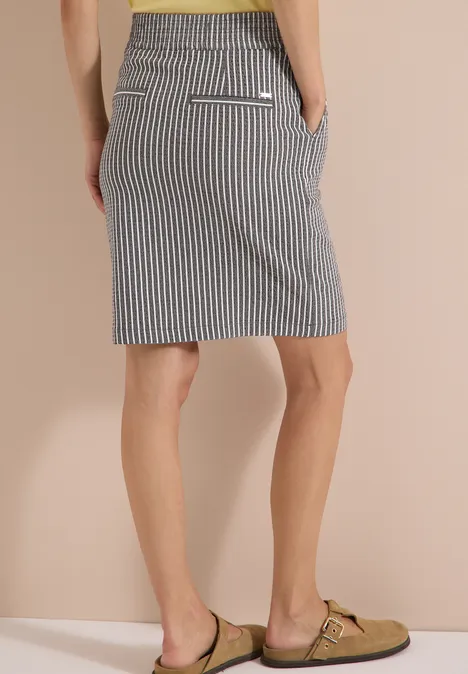 Knielanger Jogg Skirt in Seersucker-Qualität brown cacao Frau von hinten in einem gestreiften Rock und beigen Birkenstock-ähnlichen Sandalen.