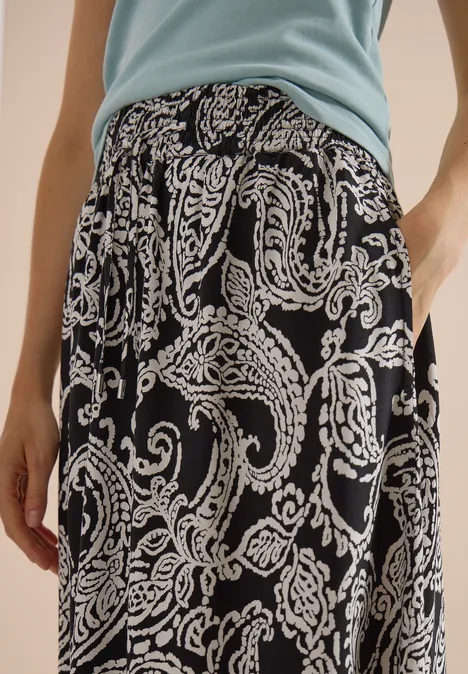 Jupe longue à motifs floraux Black Jupe mi-longue noire à motif Paisley blanc, associée à un top bleu clair.