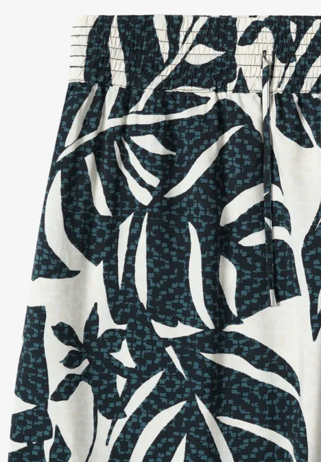Jupe blanche à taille élastique ornée de feuilles bleu foncé et de petits points turquoise.