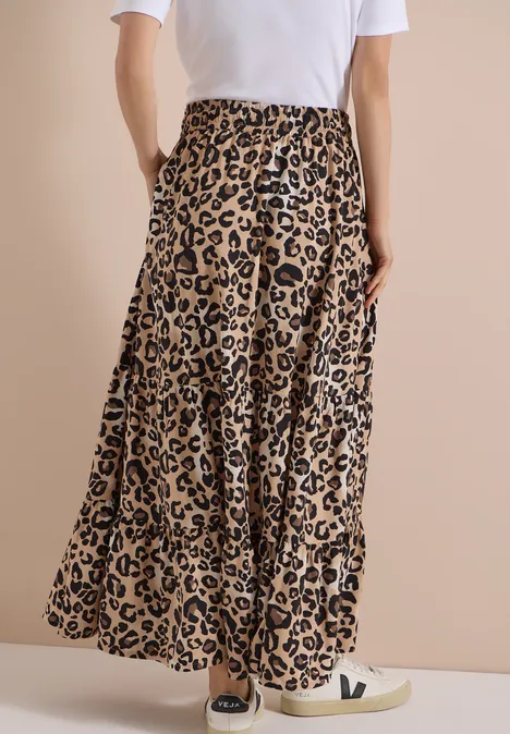 Lange geplisseerde rok met luipaardprint en hoge taille, gecombineerd met witte sneakers.