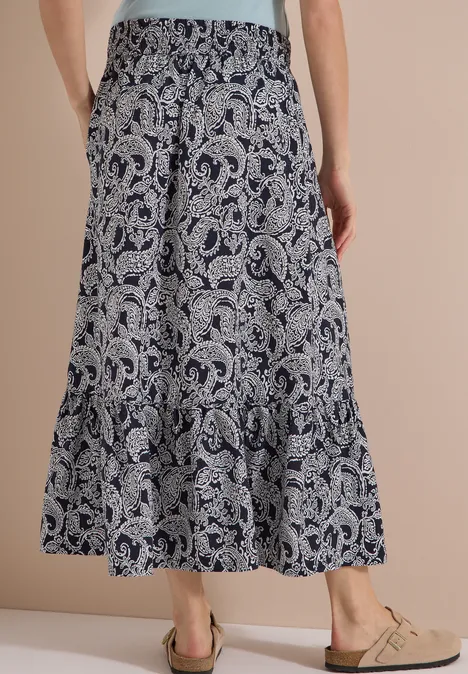 Weiß-blauer Maxirock mit Paisley-Muster, Raffung, Seitentaschen und weitem Volant, knöchellang.