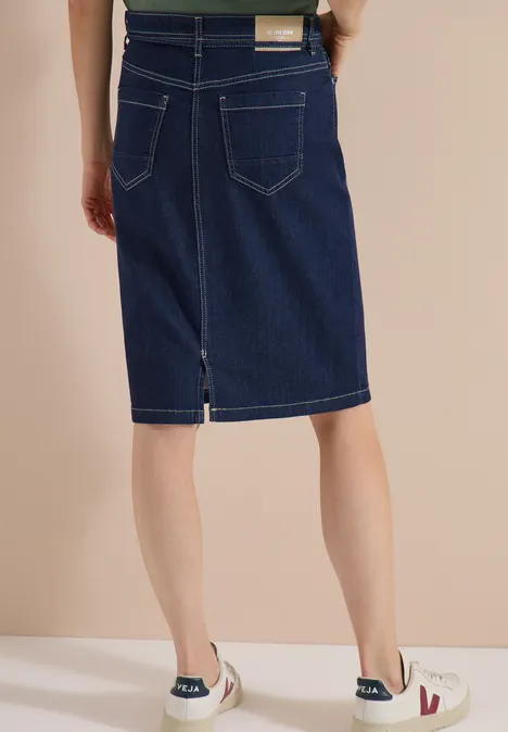 Jupe en jean arrivant aux genoux avec une ceinture rinsed wash Vue arrière d'une personne portant une jupe en jean mi-longue et des baskets blanches.