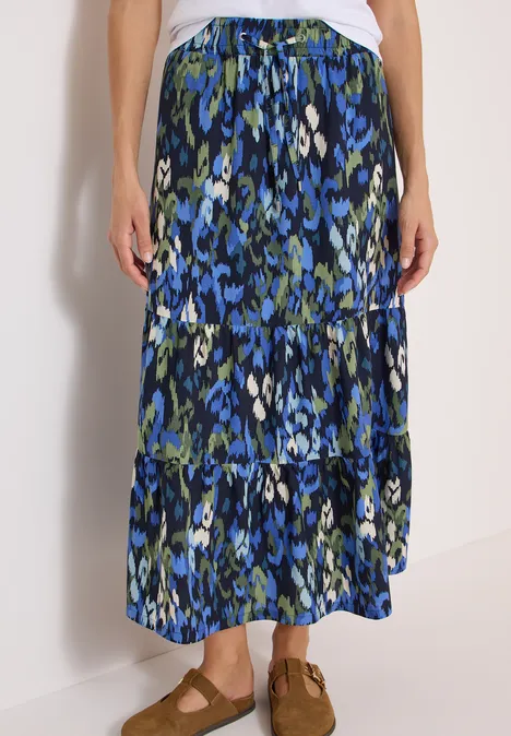 Maxirock mit Volants und Print urban dark blue Langer, gestufter Maxirock mit blau-grünem Blumenmuster und elastischem Bund, kombiniert mit braunen Sandalen.