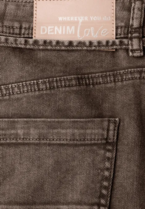 Close-up van een spijkerbroek met achterzak en label 'DENIM love'.