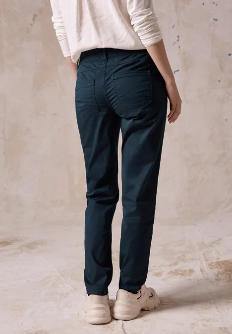 Personne en haut blanc et pantalon foncé debout de dos.