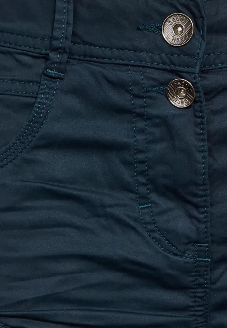 Gros plan sur un jean bleu foncé avec deux boutons métalliques et des poches.