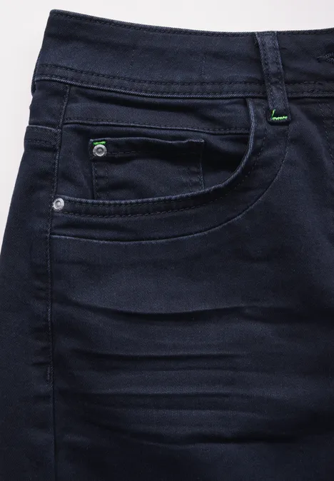 Donkerblauwe spijkerbroek met voorzak en groene stiksels.