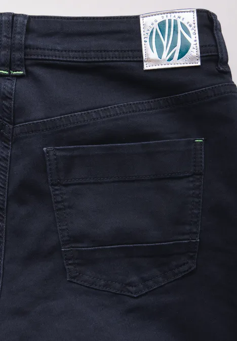 Close-up van een donkere spijkerbroek met achterzak en wit label.