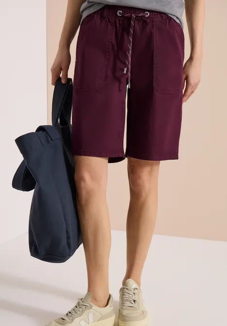 Personne porte un short violet, des baskets blanches et tient un sac bleu marine.