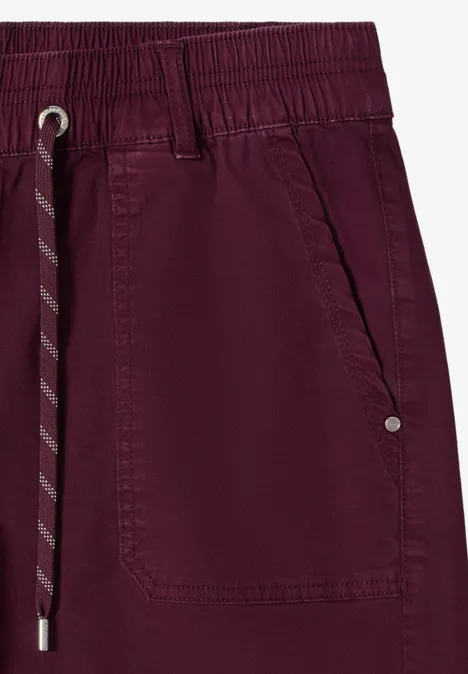 Gros plan d'un pantalon de jogging bordeaux avec ceinture élastique, cordon de serrage et poche.