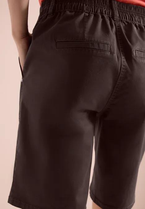 Vue arrière d’une personne portant un short sombre mi-cuisses avec poches arrière.