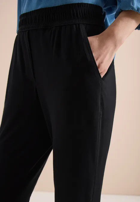 Pantalon de détente noir avec taille élastique et poches latérales, coupe décontractée.
