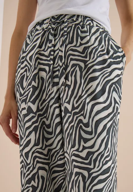 Une personne porte un pantalon zèbre noir et blanc avec cordon de serrage et poches.