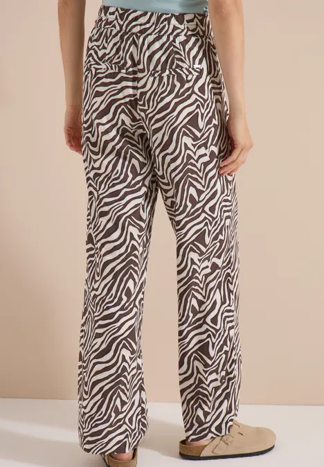 Pantalon ample à motif zèbre porté par une personne, vu de dos, avec chaussures beiges.