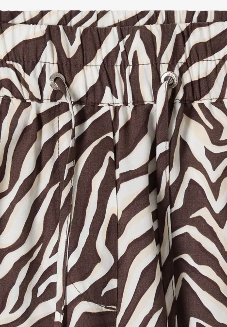 Gros plan d’un tissu marron et blanc à motif zèbre avec plis et coulisse.